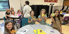 Erieview students hold up paper leaves with kind messages written on them. 