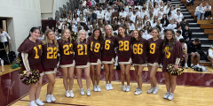 ALHS Cheerleaders stand in front of bleachers with seated senior class members seated behind them