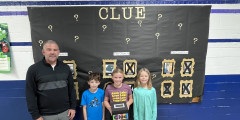 Eastview Principal Jamie Franko with students in front of a bulletin board with CLUE themed decorations. 