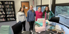 four students stand behind table holding their product prototype