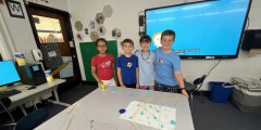 Four students stand beside table featuring a tower under construction