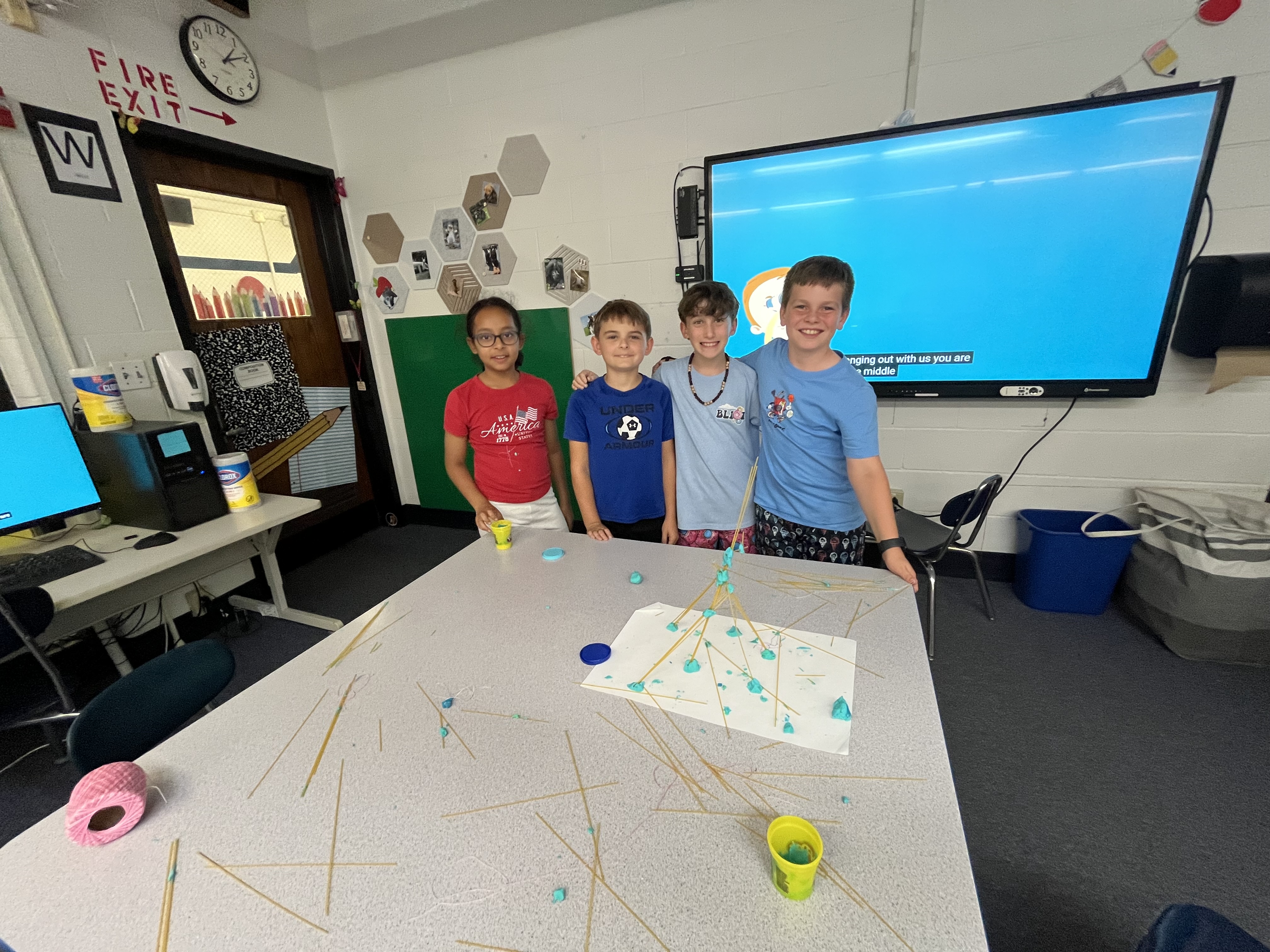 Students smile in front of their tower sitting on a desk