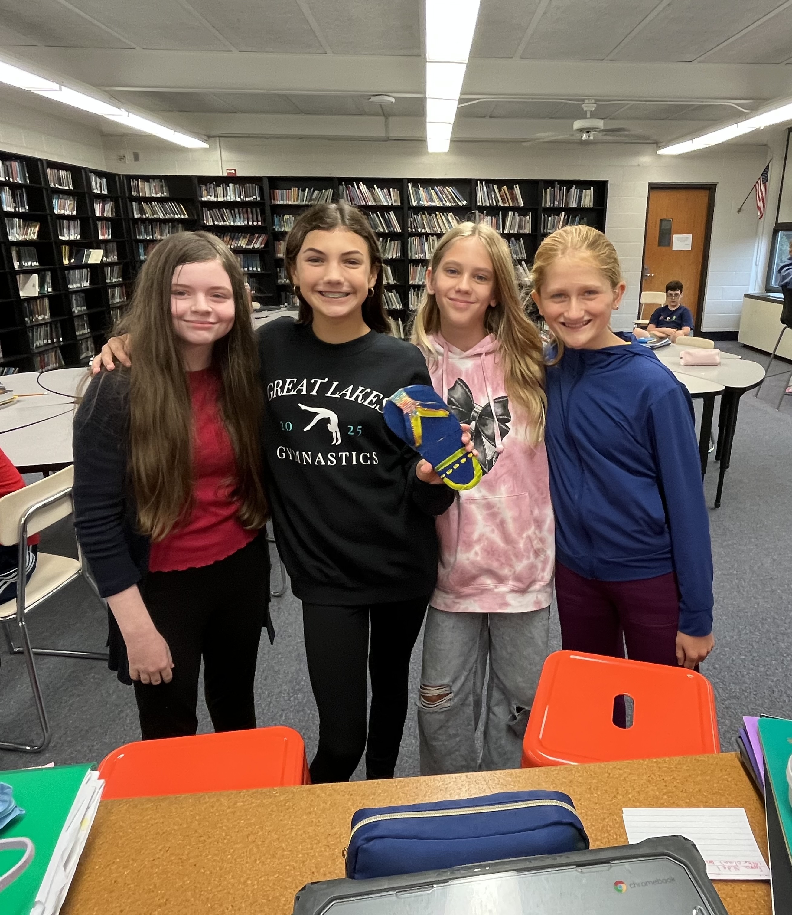 four students smile in front of a table with their product prototype