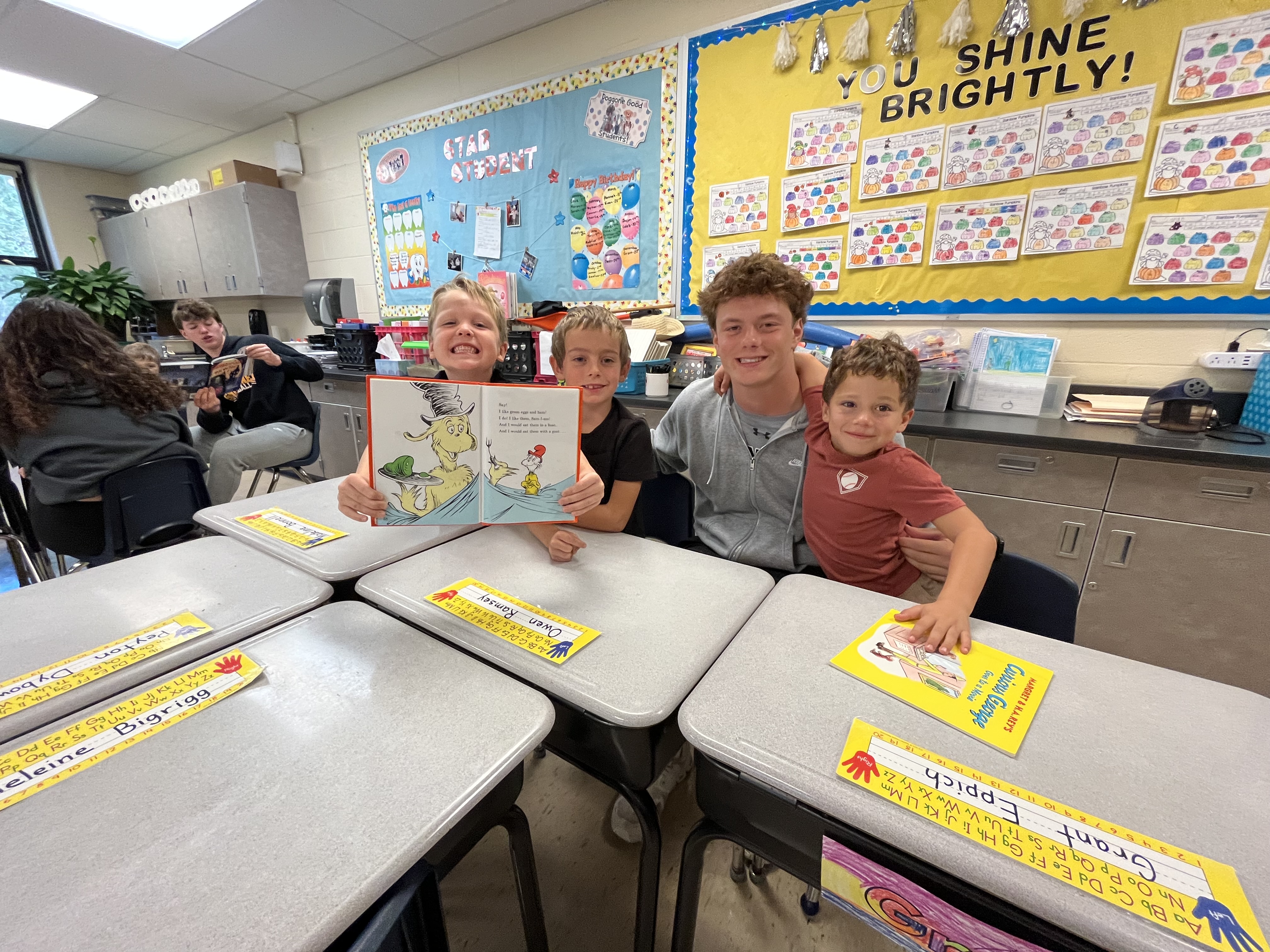 NEHS student with three Eastview students at classroom table holding books