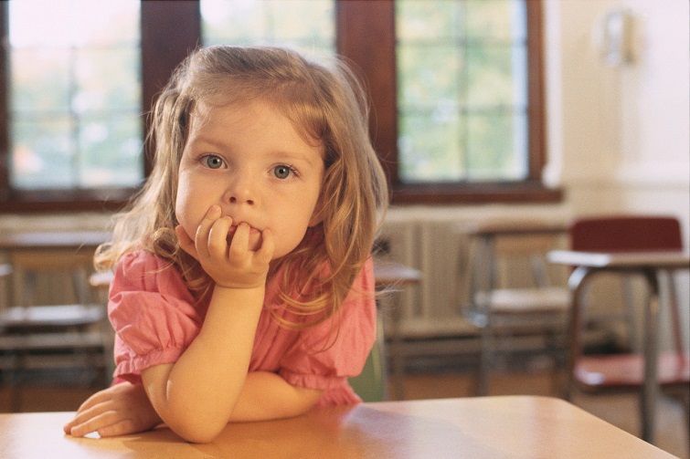 Young girl looking with elbow on desk and chin on hand